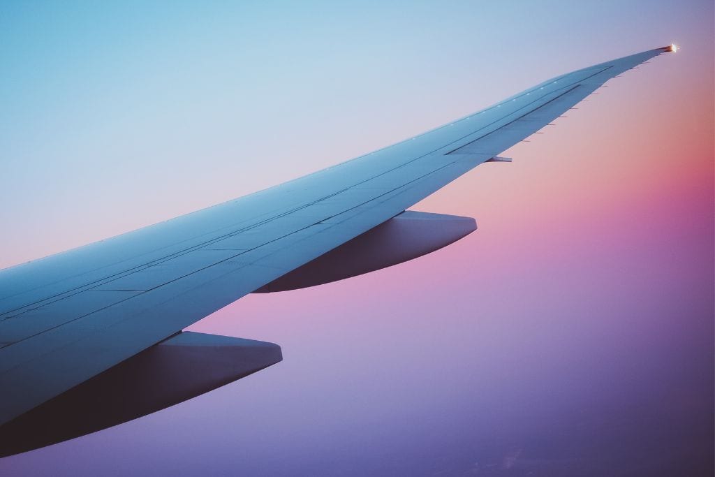 A picture of the plane wing with the sunset in the background.