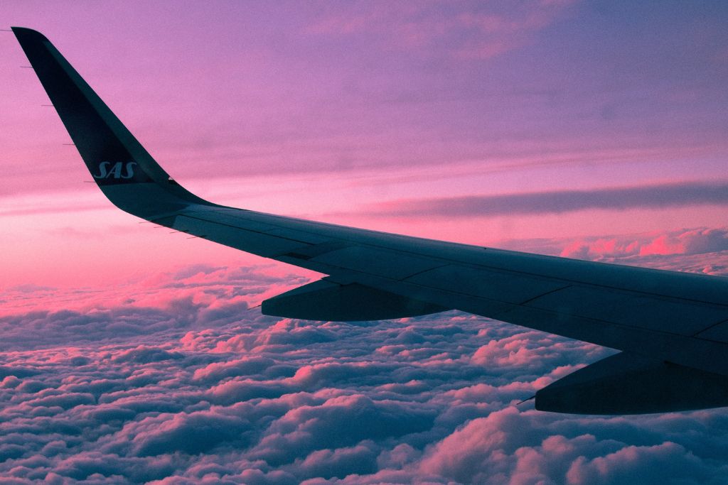 A picture of a plane flying at sunset.