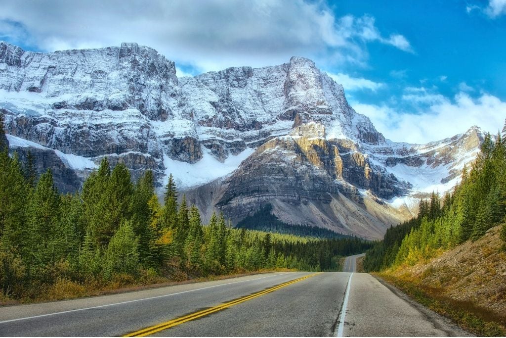 A picture of the road and incredible views along Icefields Parkway. Driving along part of this stretch of the road is the eighth thing to do in our travel guide to Banff.