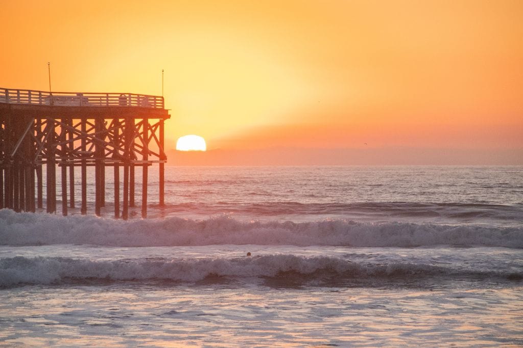 A picture of a bright orange-yellow sunset at Pacific Beach with the pier in the background.
