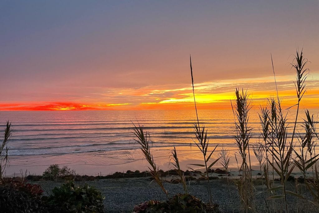 A picture of Del Mar at with a bright red and orange sunset. Surfing at sunset at Del Mar is always recommended!