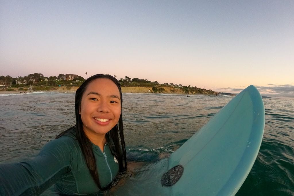 A selfie of Kristin smiling while surfing in San Diego.