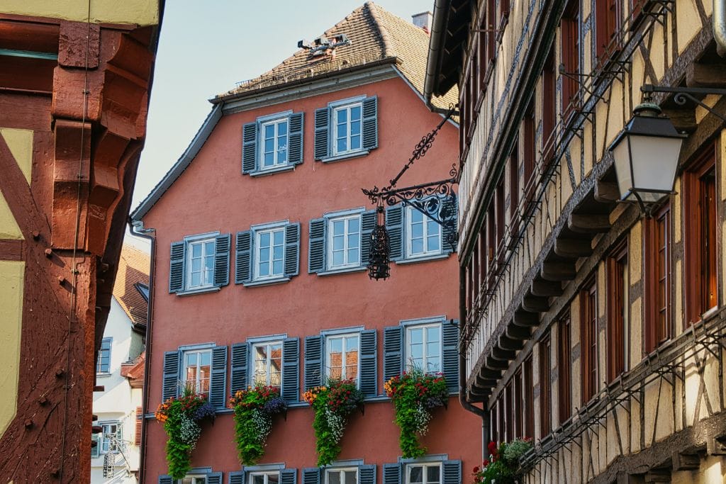 A picture of a red half-timbered house with stunning flowers draping from various window gardenboxes.