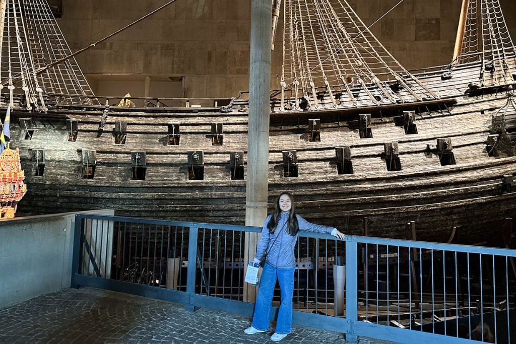 A picture of Kristin smiling at the Vasa museum in Stockholm, Sweden with the Vasa ship behind her.