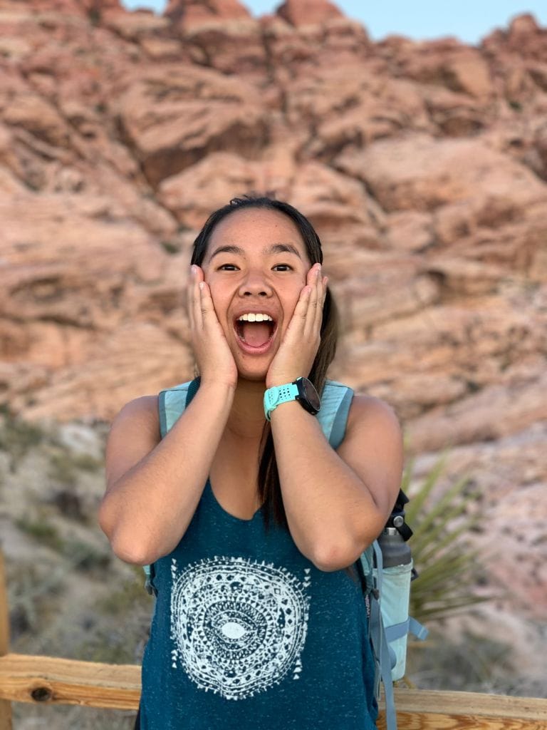 A picture of Kristin smiling with her mouth open and her hands clasping her cheeks! The famous red rocks are in the background. This is likely how you'll also feel after taking a horseback riding tour through Red Rock Canyon! 