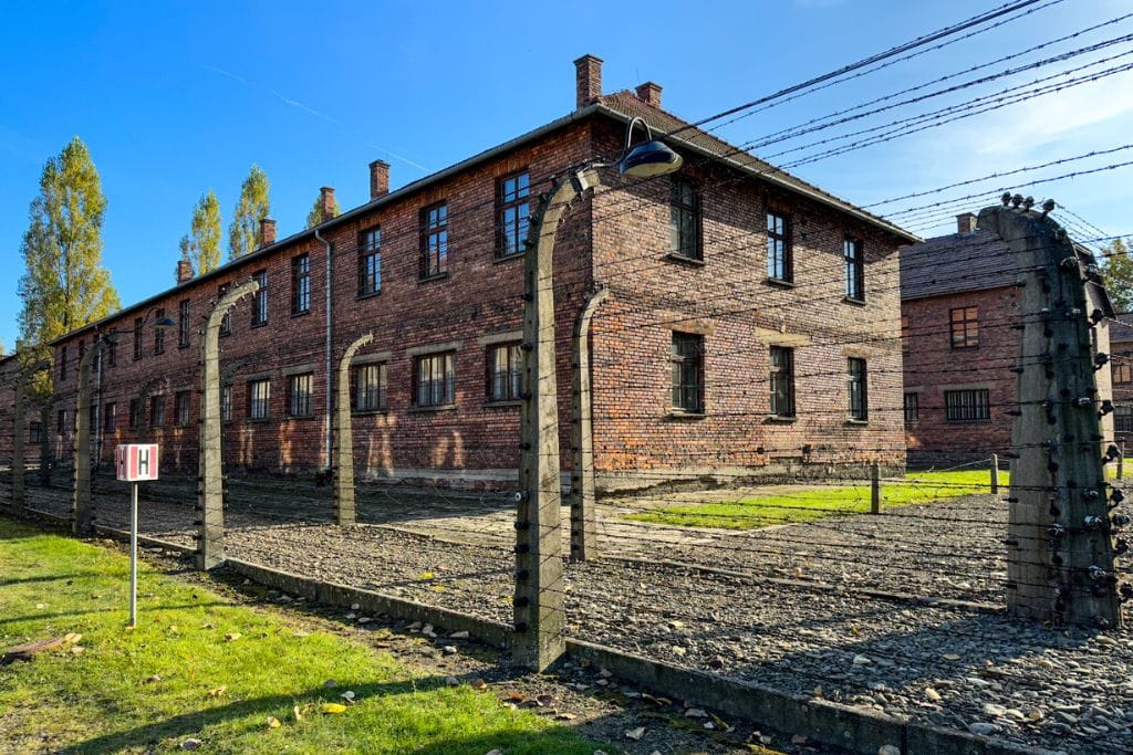 A picture of the two wired fences that enclose Auschwitz I camp. You will walk along the fence on your day trip to Auschwitz from Krakow.
