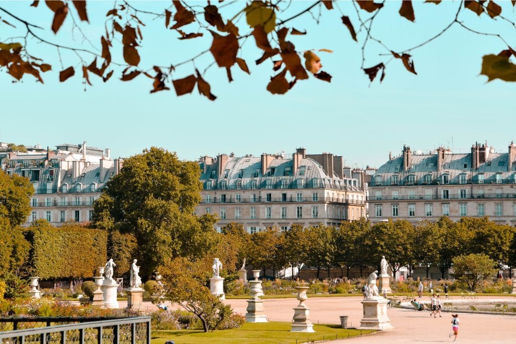 A picture of a park in France with the beautiful architecture in the background
