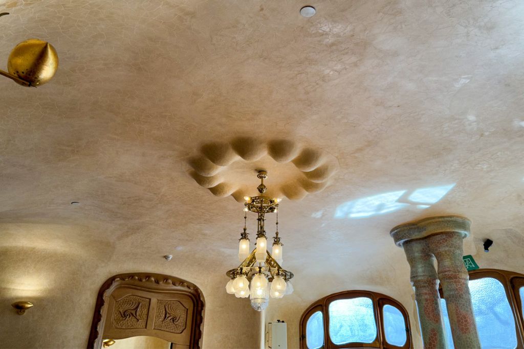 A picture of the ceiling in the dining room on the Noble Floor of Casa Batlló. There are several mini domes surrounding the center chandelier. 