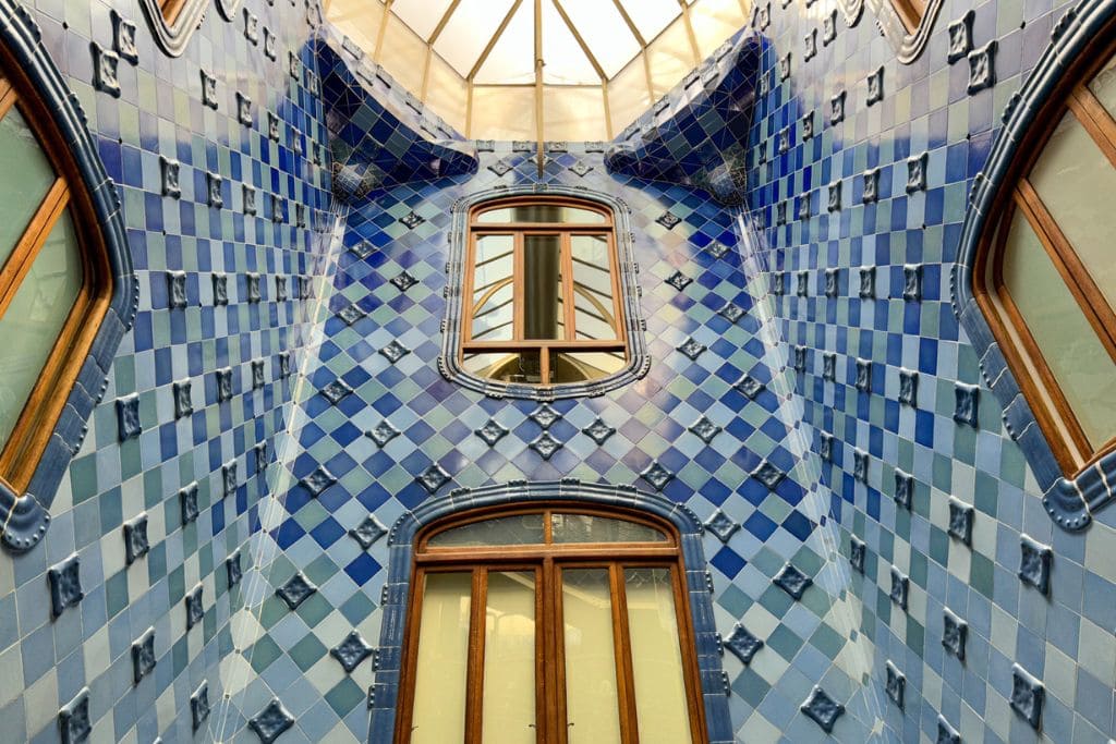 A picture of the lightwell that can be found inside Casa Batlló. There are darker blue tiles at the top and they gradually become lighter towards the bottom. 