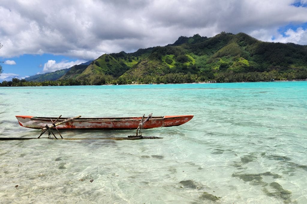 A picture of a traditional French Polynesian boat resting in clear blue waters off of Moorea.