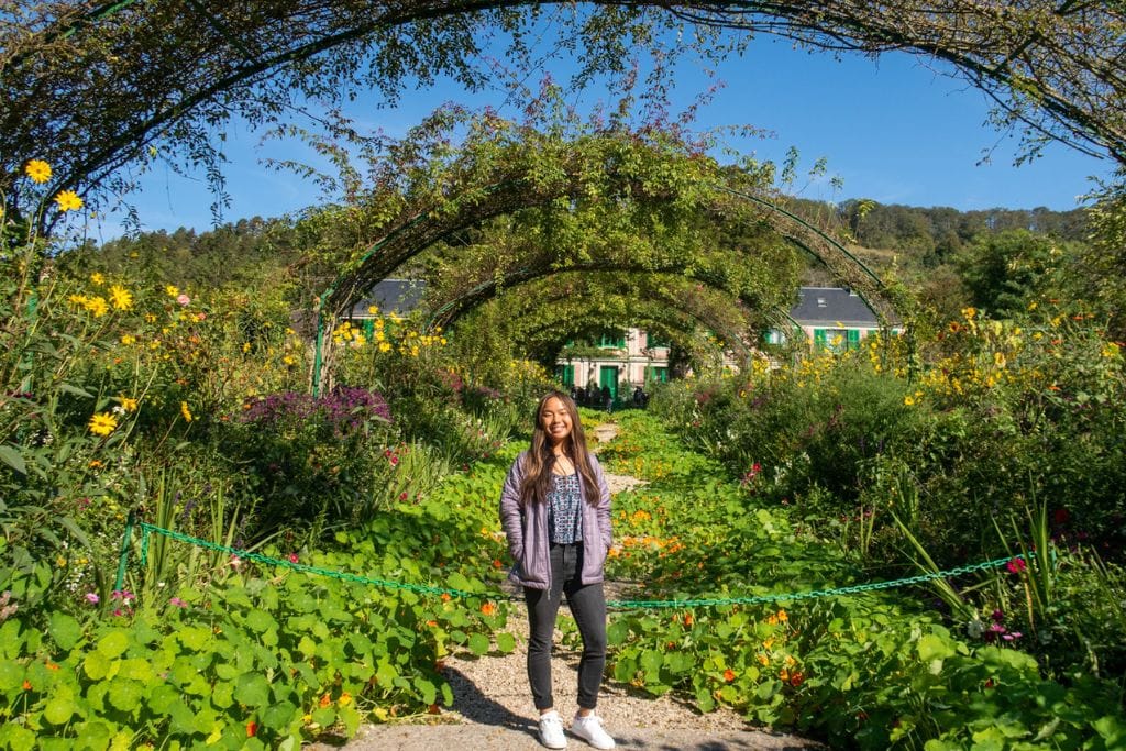 a picture of Kristin standing underneath the arches that can be found in Monet's gardens. You can roam through Monet's Gardens and see all the blossoming flowers if you visit Monet's estate on a Day Trip from Paris to Giverny.