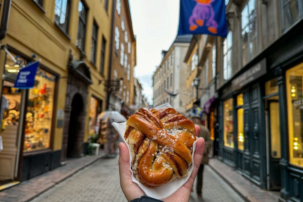 A picture of Kristin holding a traditional Swedish cinnamon roll in Gamla Stan. An absolute must during your 3 days in Stockholm is to partake in Fika!