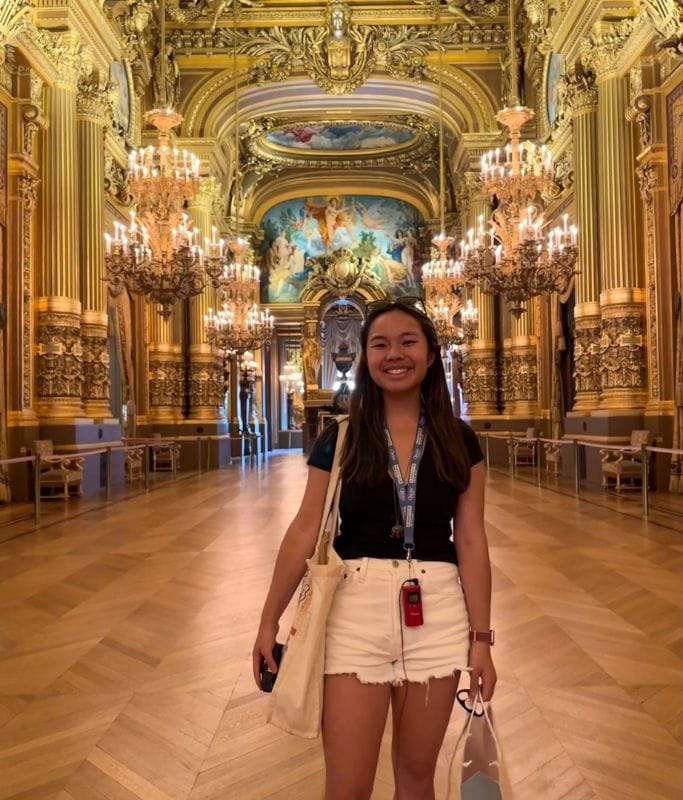 A picture of Kristin standing in the great hall of the Paris Opera House. The ornate interior is comparable to the Galleries in Milan.