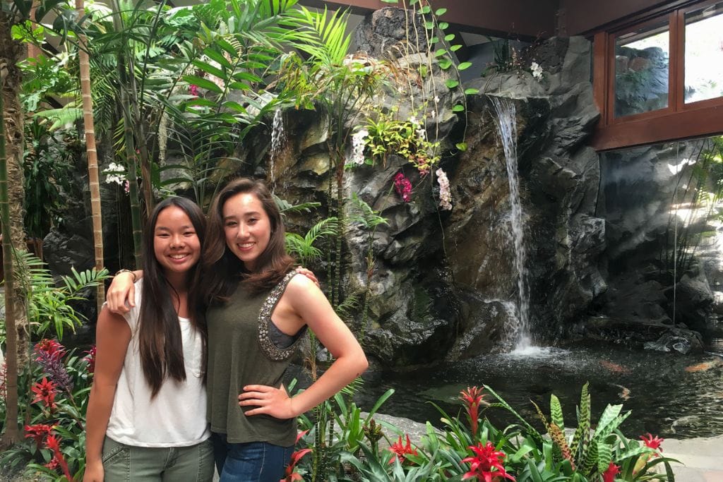 A picture of Kristin and her friend in front of a waterfall that's inside the Catamaran Resort and Spa.