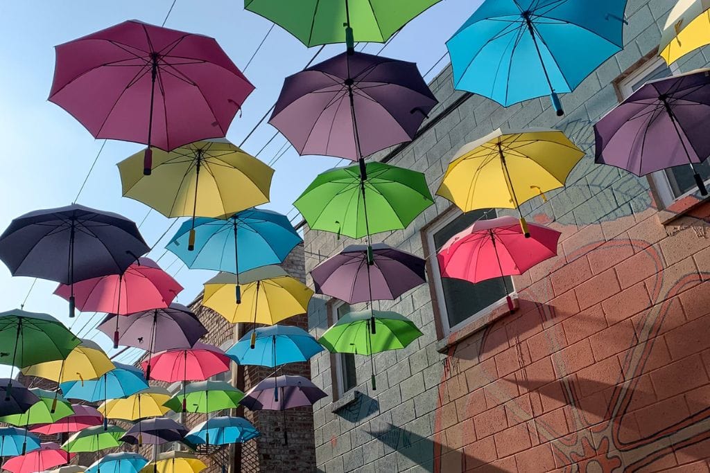 A picture of the colorful umbrellas found in the Orange Street Alley in downtown redlands. You can also see the little street artwork.