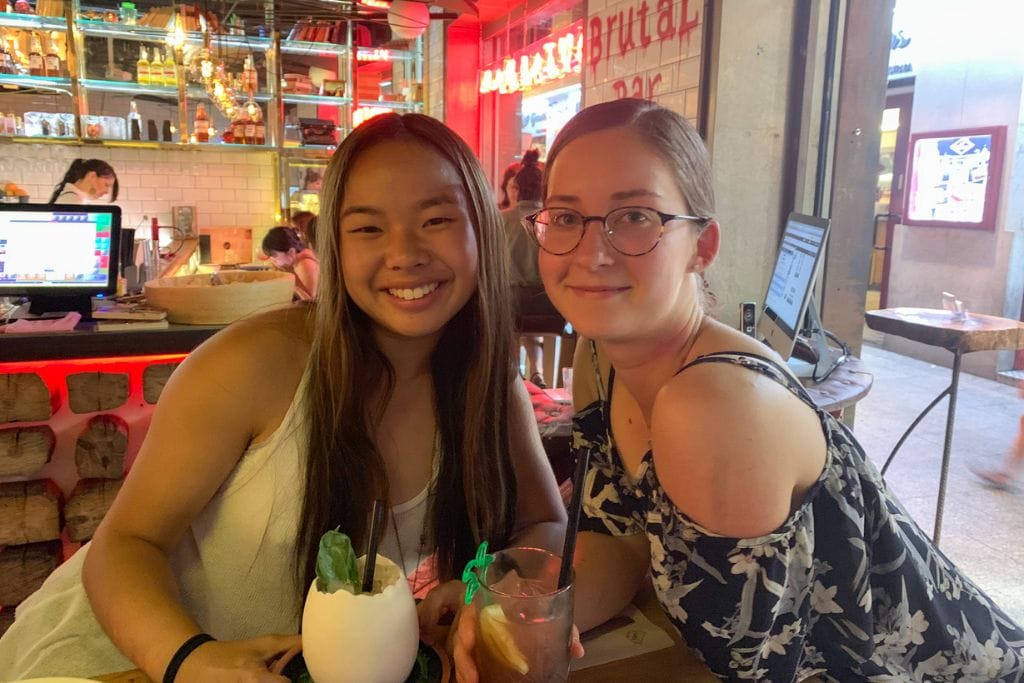 A picture of Kristin and her friend at enjoying some cocktails at a bar!