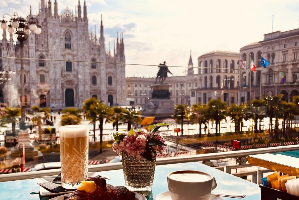 A picture of some drinks on a table with the Duomo di Milano in the background.