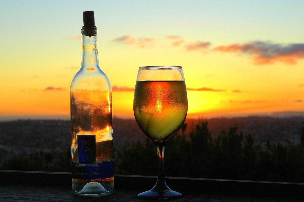 A picture of a bottle and glass of wine with a beautiful San Diego sunset in the background. 