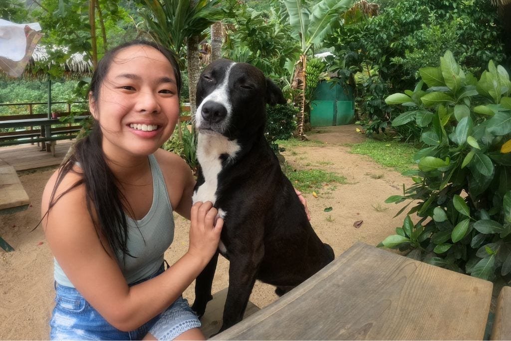 A picture of Kristin smiling with a dog at the Moorea tropical garden.