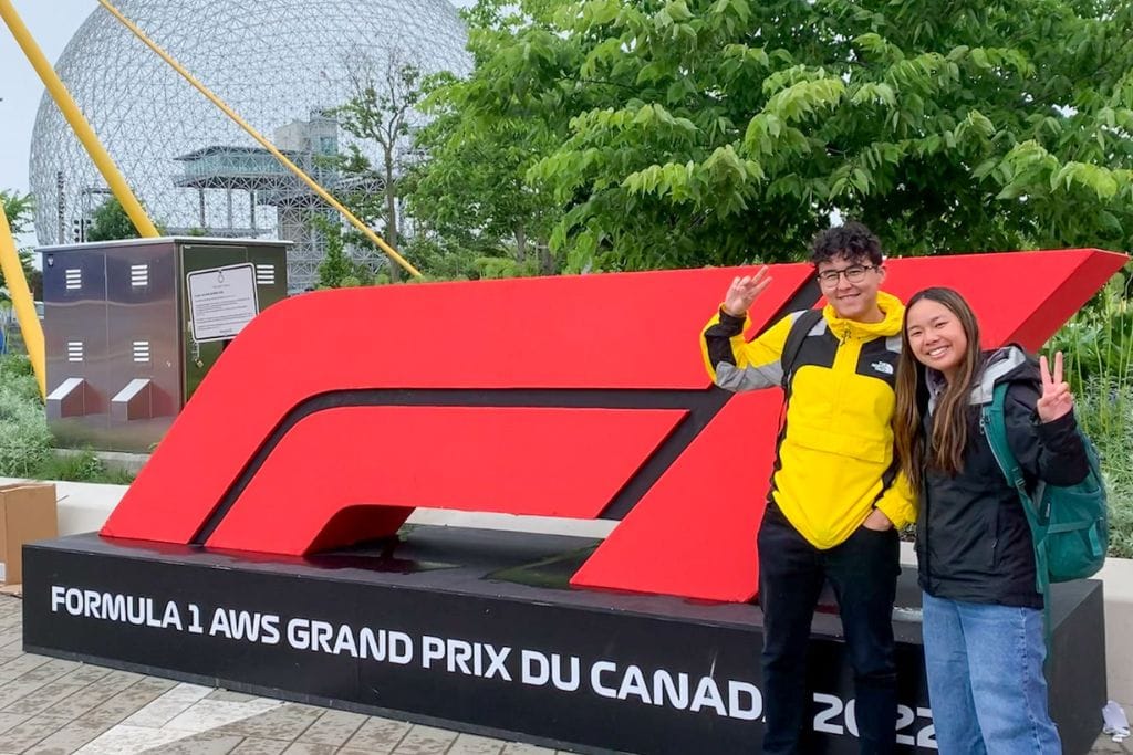 A picture of Kristin and her friend standing in front of the F1 TV sign.