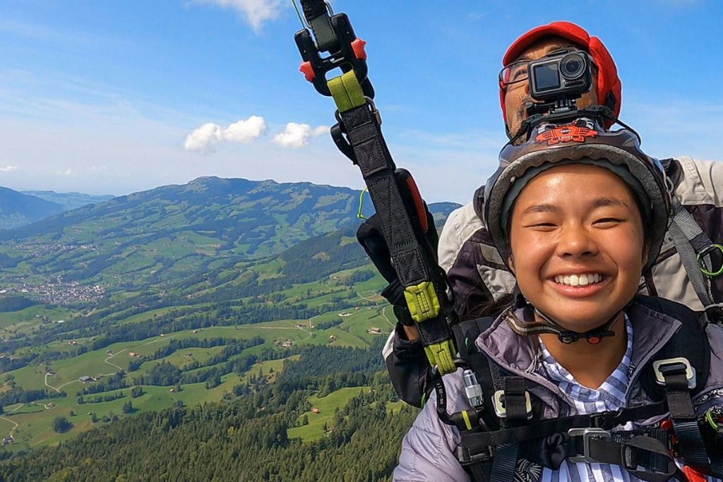 A picture of Kristin paragliding in Switzerland. Don't forget to document your incredible experience with a memorable instagram post and a great caption!