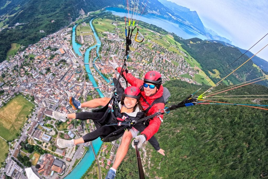 A picture of Kristin and her pilote paragliding with the gorgeous scenery of interlaken in the background