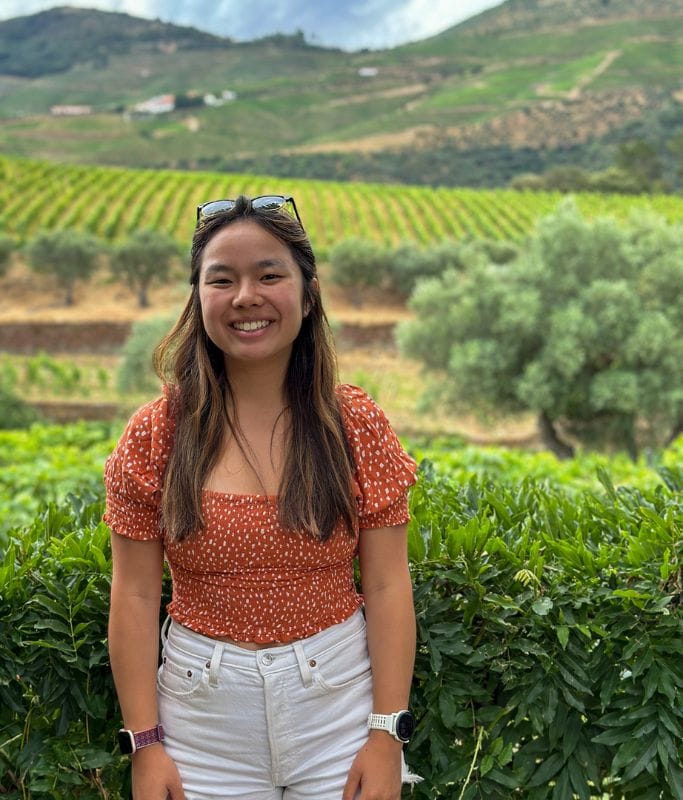 A picture of Kristin standing in front of a bunch of vineyards on her wine-tasting tour.