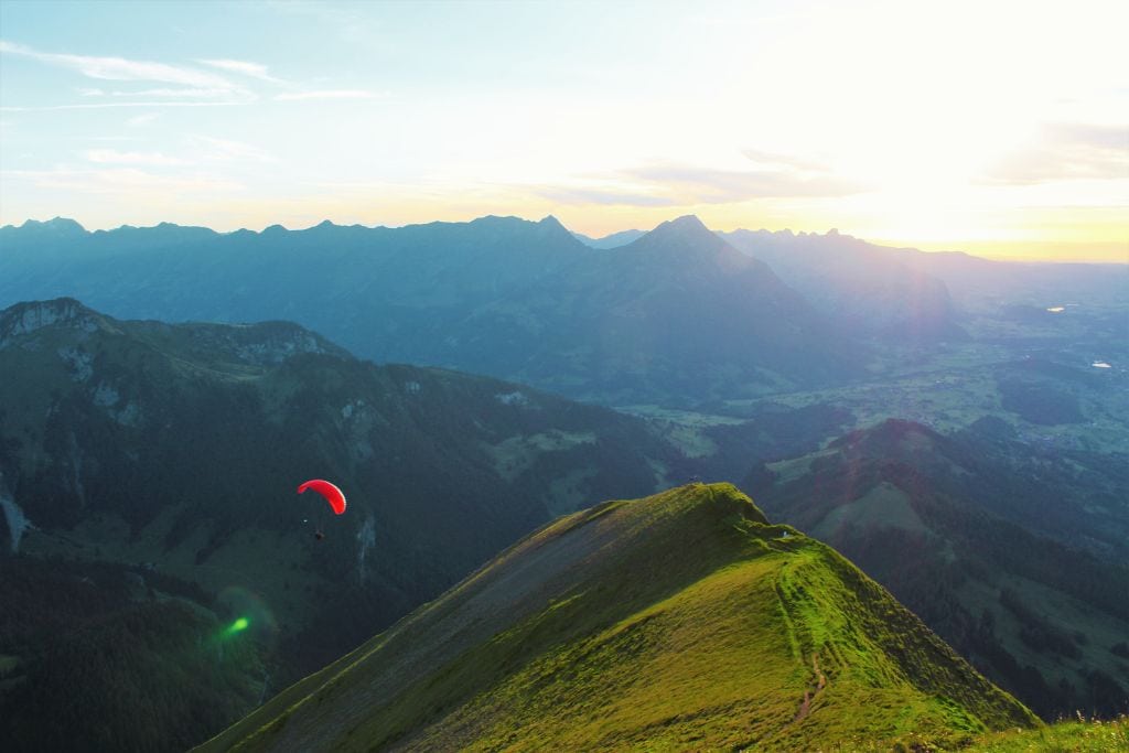 A picture of a person paragliding during sunrise.