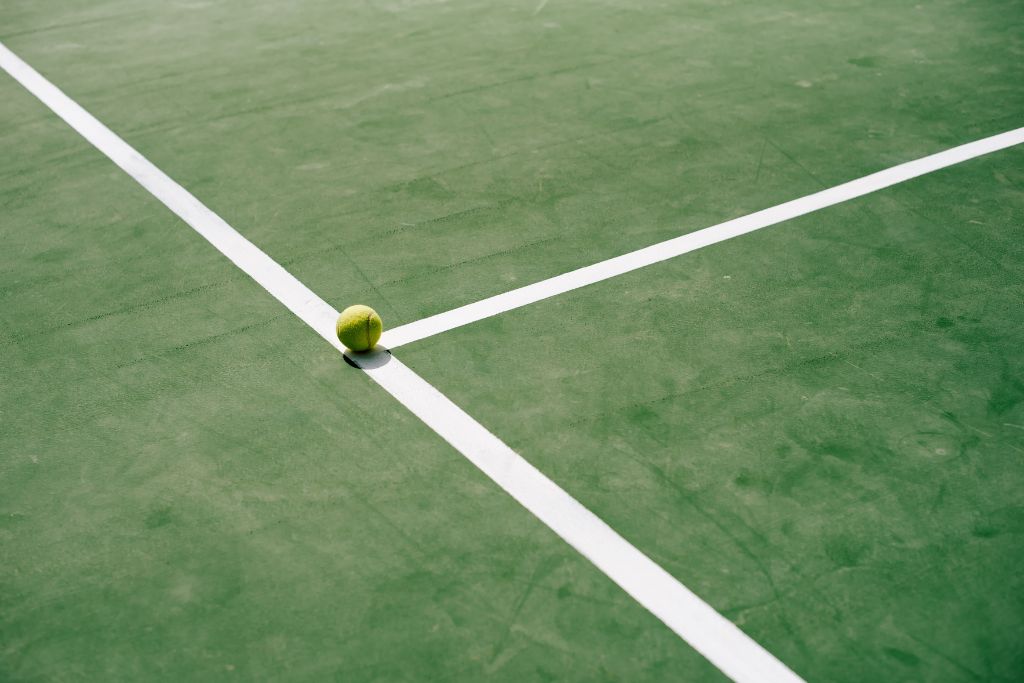 A picture of a tennis court with a tennis ball on the T.