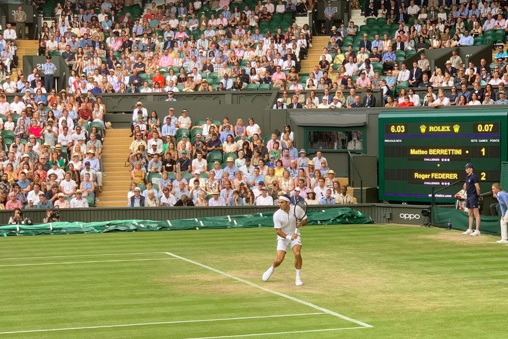 A picture of Roger Federer getting ready to slice a tennis ball back at Wimbledon on Centre Court. A perfect tennis caption would be: Effortless beauty from the Maestro!