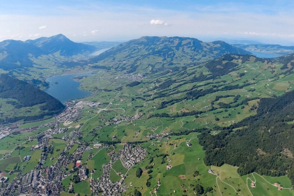 A picture of the verdant valley below and super blue lakes in Schqyz Switzerland, as seen from above while paragliding.