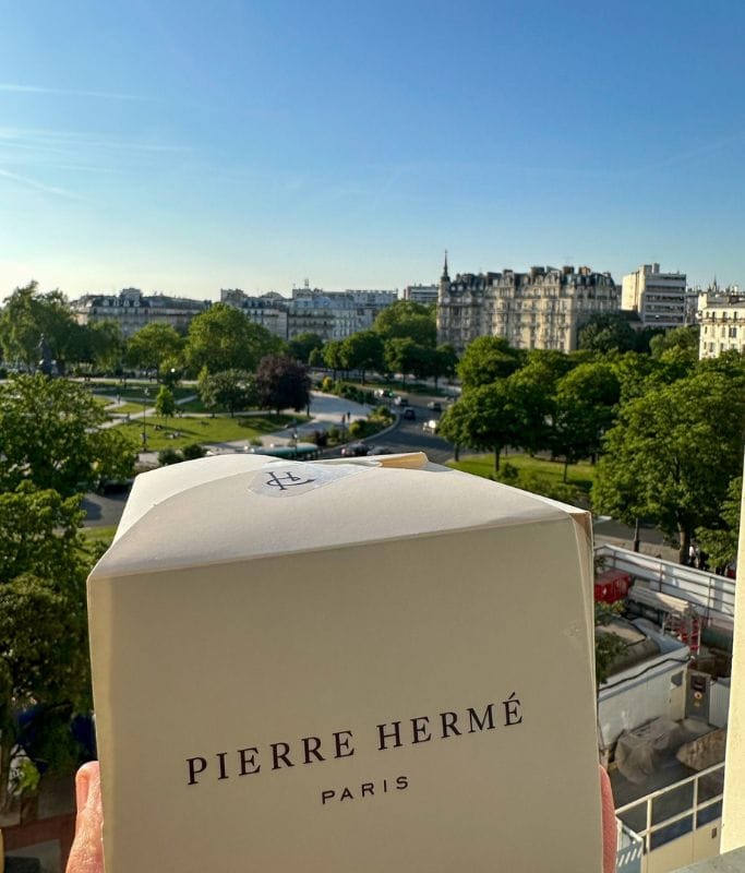 A picture of Kristin holding a box of gourmet pastries from Pierre Herme.