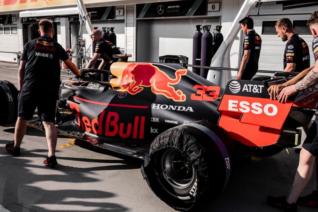 A picture of Max's car and part of the Red Bull Pit crew wheeling his car in the pitlane.