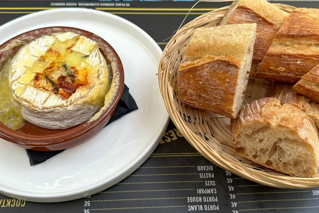 A picture of camembert and pieces of a French baguette. One of the best things to do in Biarritz is eat the local French and Basque food!