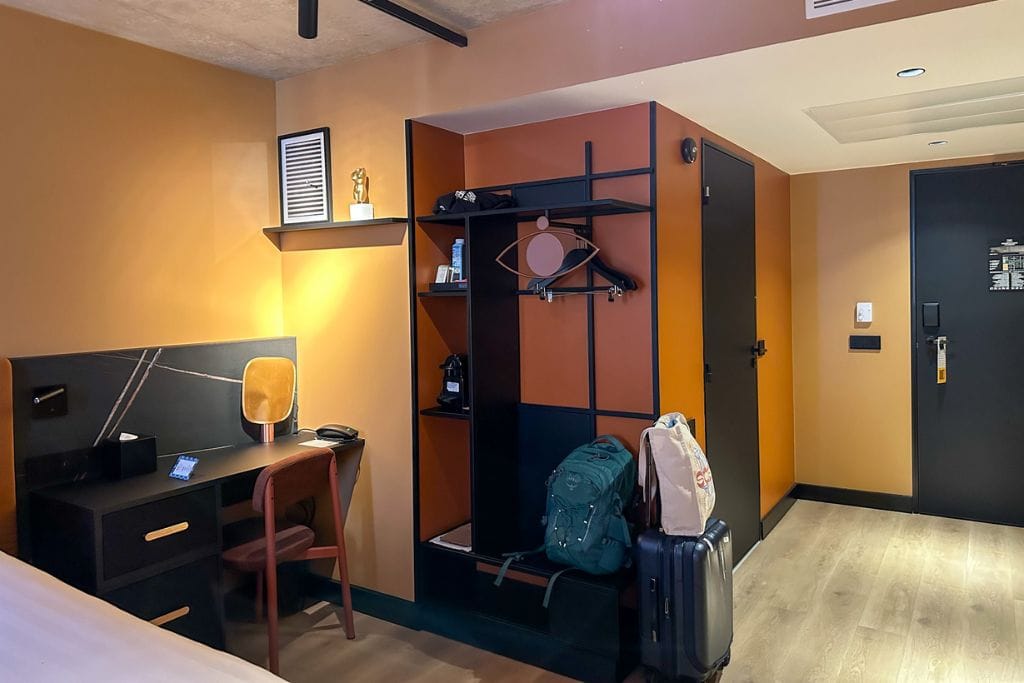 A picture of the tasteful decorations in Tribe Hotel Paris Saint Ouen. You can see the office/desk area, the clothing rack with plenty of storage, and the coffee machine.