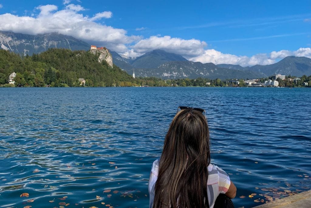 A picture of Kristin, sitting on the docks of Bled island, taking in the peaceful atmosphere. Lake Bled is likely well worth visiting for those keen on an escape from city life.