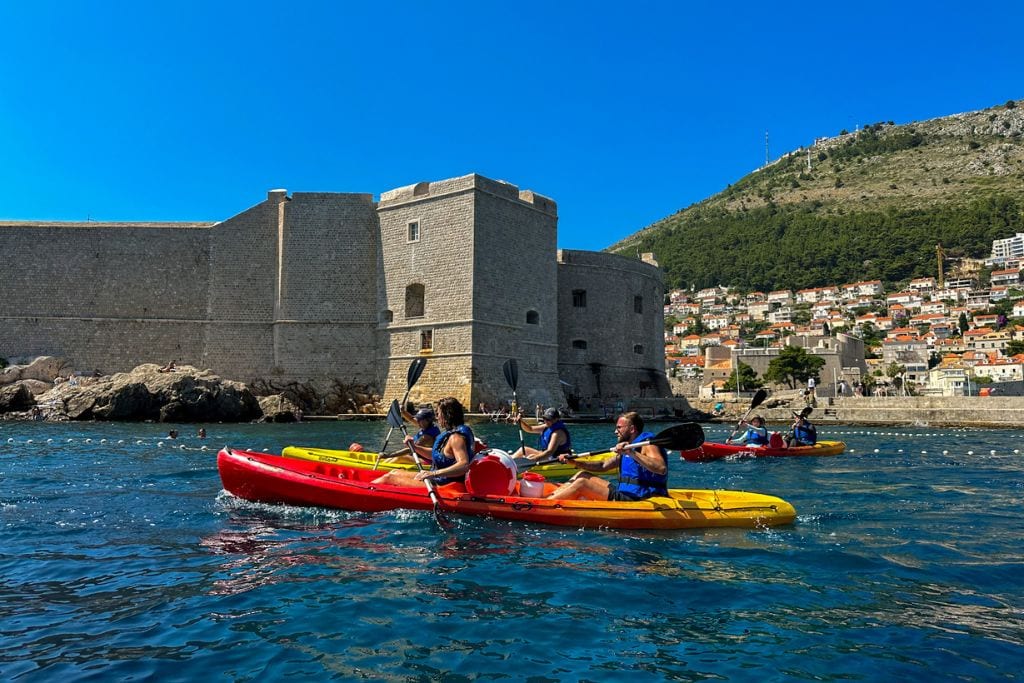 A picture of people kayaking past the Dubrovnik city walls.