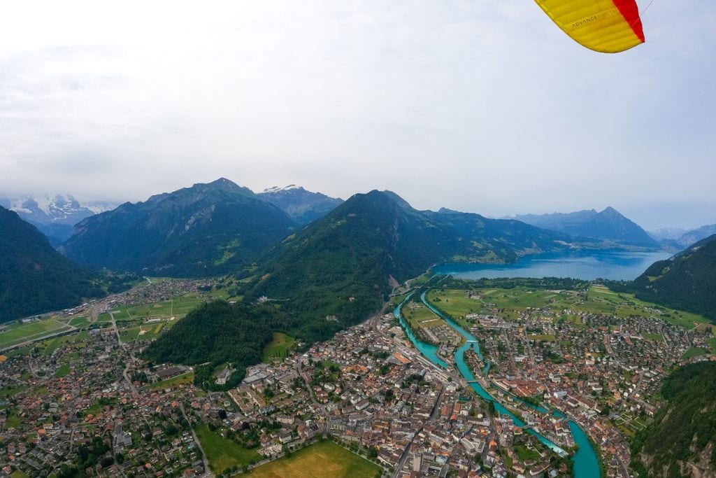 A picture of Interlaken and the beautiful surrounding taken while paragliding in Interlaken. You can see the tip of the yellow paraglider wing.