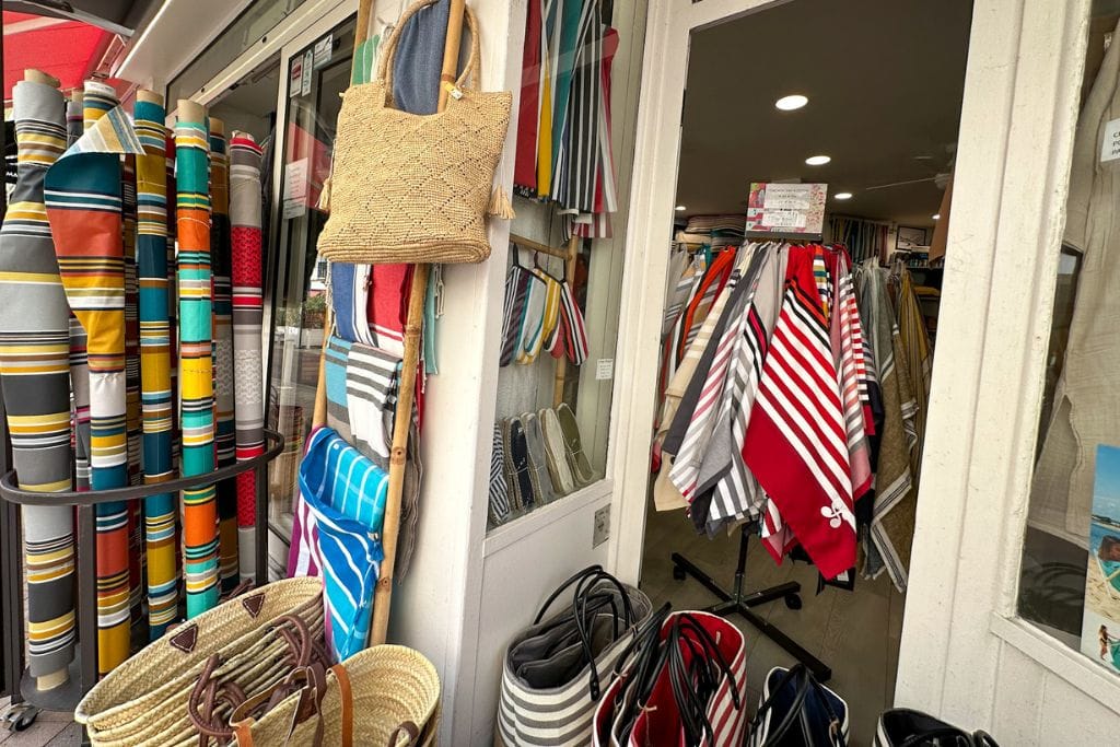 A picture of some colorful fabrics and woven tote bags in a small shop along Rue Mazagran in Biarritz.