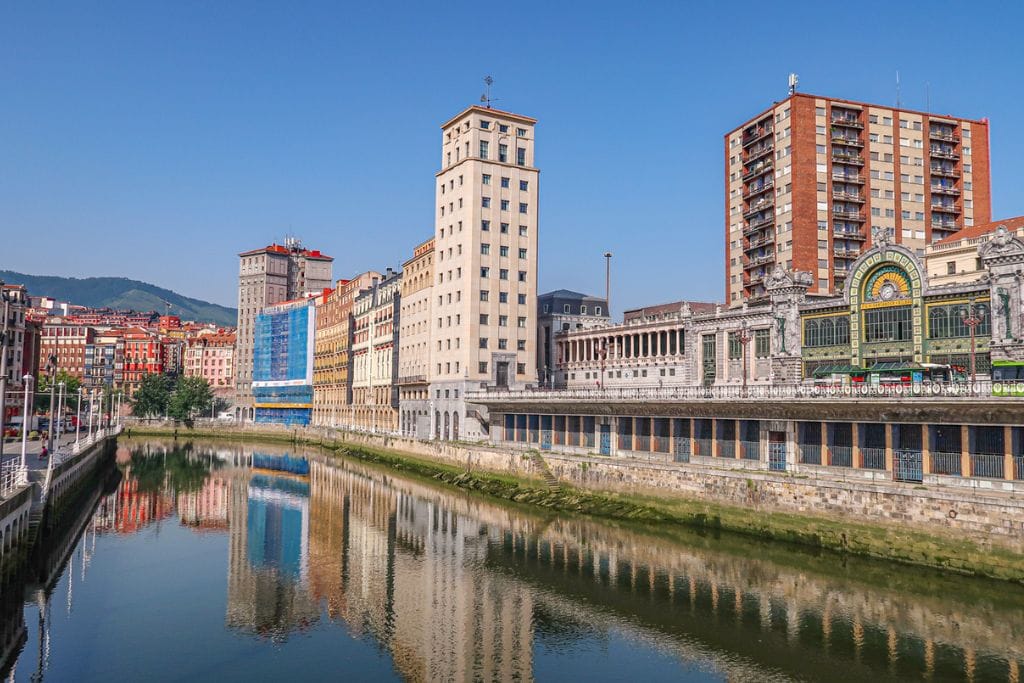 A picture of the colorful buildings that can be found in Bilbao. You can also see the River Nervion, which runs through the city. For those looking for a change in pace, a day trip to Bilbao is a fun thing to do.