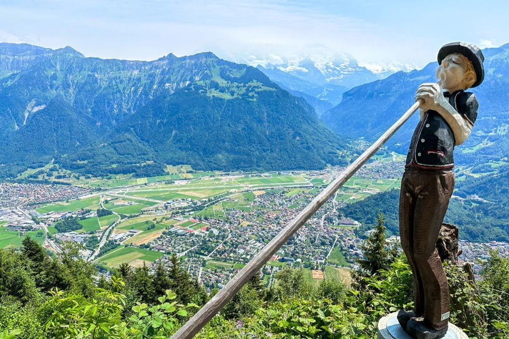 A picture of Interlaken as seen from the top of Harder Klum. There's also a little wooden statue of a Swiss man with an alphorn.