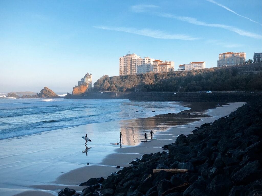 A picture of Plage De La Côte Des Basques with some surfers walking along the shore. I highly recommend surfing, even if you're a beginner, during your 2 days in Biarritz.
