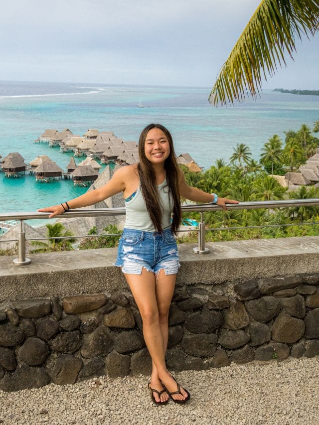 A picture of Kristin in Moorea with overwater bungalows in the background.