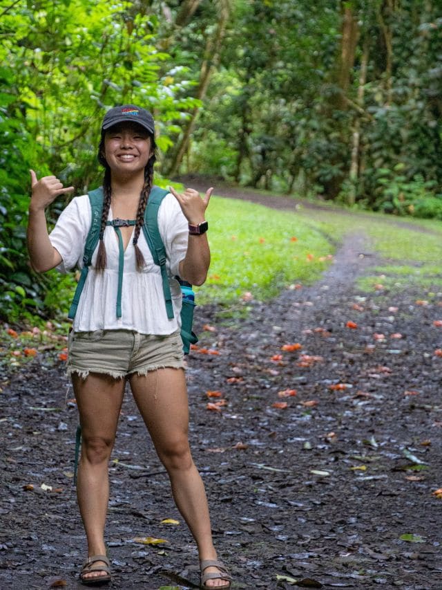 A picture of Kristin hiking through the bright green interior of Tahiti.