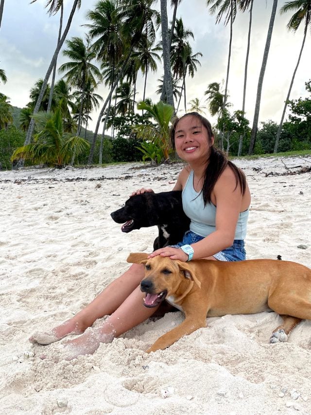 A picture of Kristin petting two stray dogs in French Polynesia