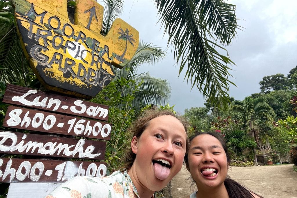 A picture of Kristin and her friend posing in front of the Moorea Tropical Gardens sign.