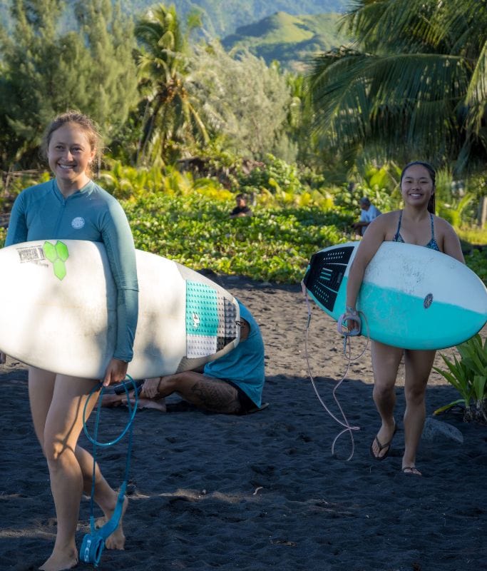 A picture of Kristin and her friend heading out for a surf sesh at Papara in Tahiti.