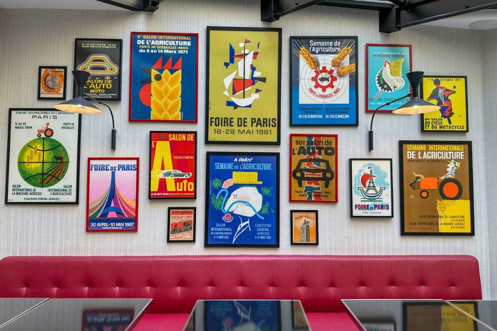 A picture of several French themed posters decorating a wall in the breakfast room of Hotel Moderniste in Paris.
