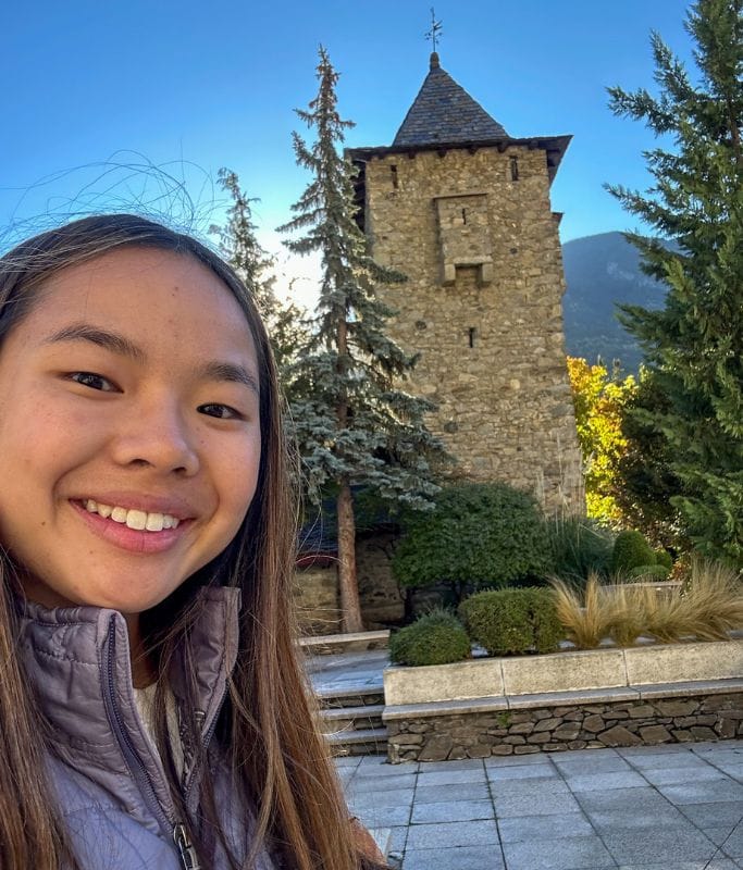 A picture of Kristin in Andorra with a historic building in the background.