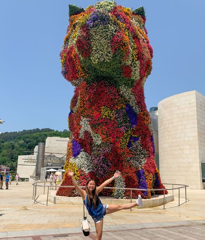 A picture of Kristin in front of the dog flower structure that's outside of the Guggenheim.